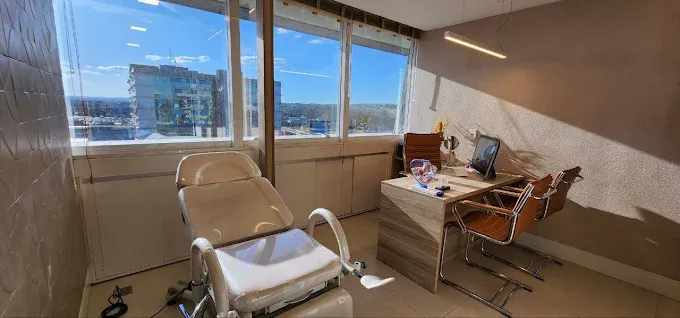 Sala de atendimento com cadeira ginecológica e ampla janela com luz natural, promovendo bem-estar e conforto durante a consulta.