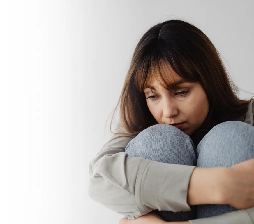 Mulher sentada com expressão de tristeza, representando sintomas de depressão e a importância do cuidado emocional.